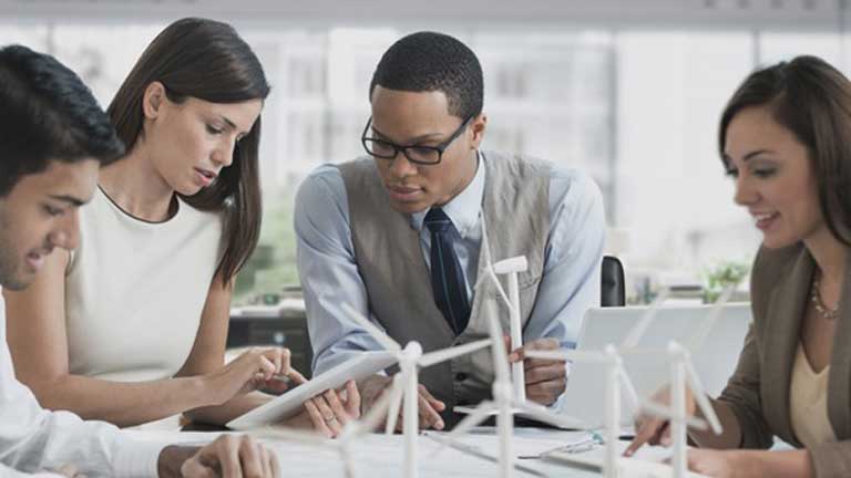 Four people sitting at a table collaborating on a project