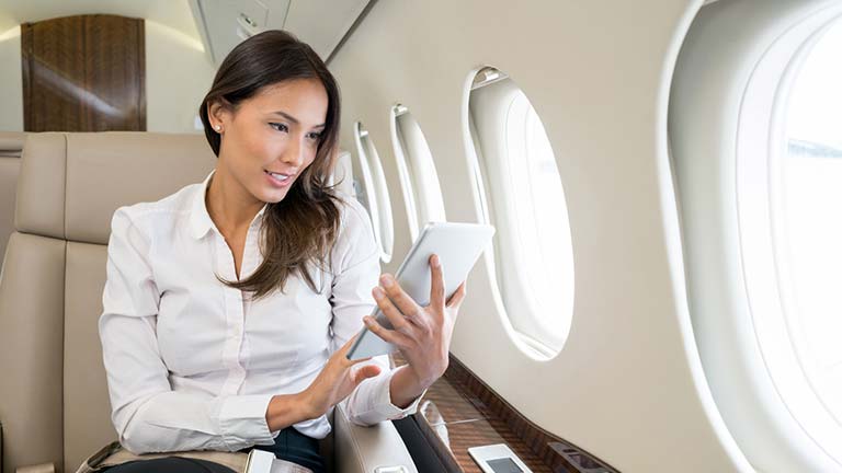 woman looking at tablet on airplane