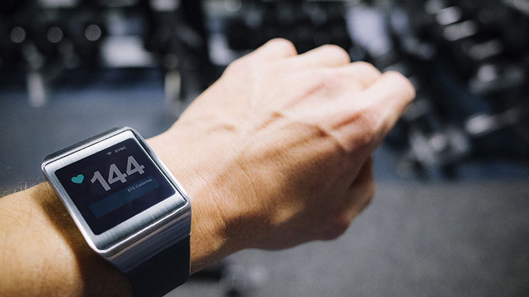 Smart watch worn on a wrist showing pulse rate.
