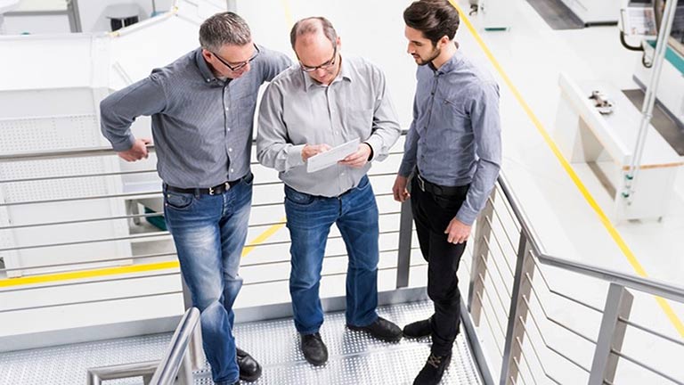 Three men standing in stairwell talking